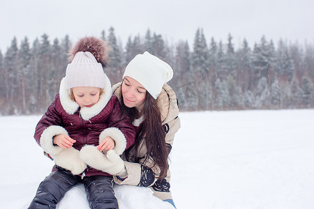 幸福的妈妈和孩子家庭享受冬天的雪天
