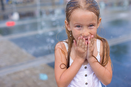 炎热阳光明媚的日子里，街头喷泉里湿漉漉的快乐小女孩的画像