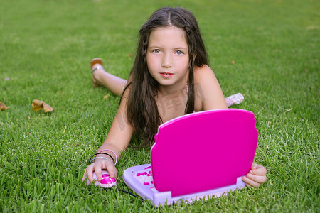 粉色玩具摄影照片_玩粉色玩具电脑的漂亮小女孩