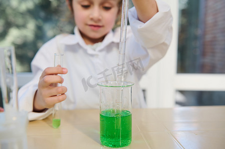 有选择地关注一个模糊的聪明女学生手中装有绿色化学液体和刻度吸管的烧杯
