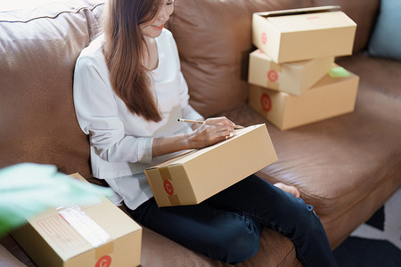 独立亚洲女性在线卖家包装产品的小型企业企业家发送给客户和中小企业交付概念