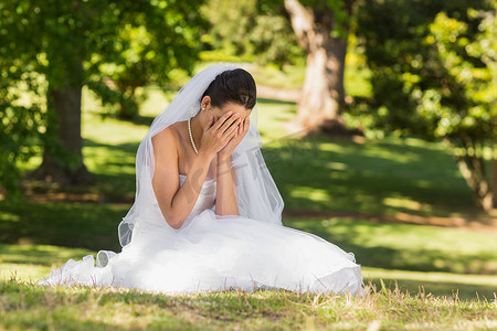 坐在公园的美丽的担心的新娘