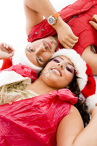 快乐的年轻夫妇戴着圣诞帽躺在地上