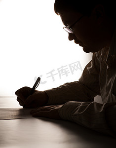 剪影任务摄影照片_剪影男人正在一张纸上写字