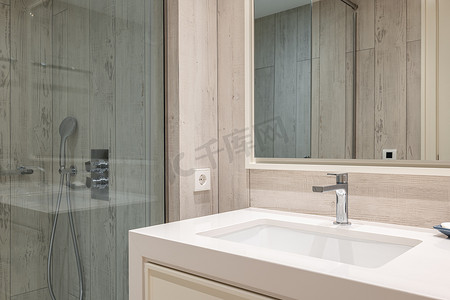 明亮的浴室特写，配有木质效果面板墙、方形陶瓷水槽，大理石台面上有水龙头，墙上有镜子。