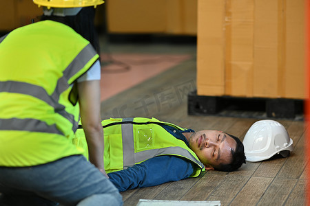 仓库工人躺在水泥地上失去知觉，同事们帮助受伤的人进行急救