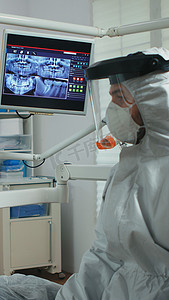 放射防护摄影照片_带面罩的医生指着口腔监护仪