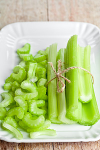 芹菜茎摄影照片_盘子里的一捆新鲜绿色芹菜茎