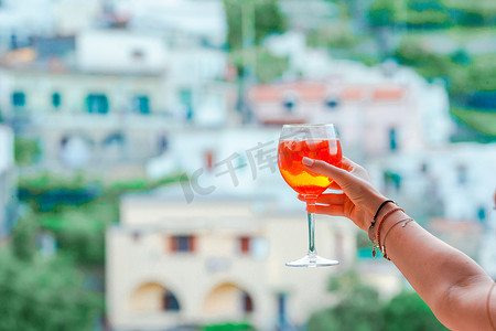 阿马尔菲海岸摄影照片_阿马尔菲海岸美丽的意大利古老村庄，带有 Spritz Aperol 酒精饮料背景的玻璃杯
