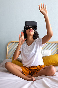 年轻的多种族拉丁裔女性在家中使用 VR 眼镜移动双手触摸 3D 世界中的物体。