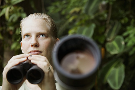 雨林中带双筒望远镜的漂亮女人