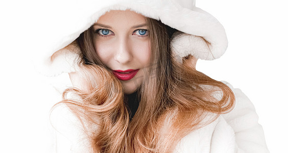 战帽摄影照片_穿着蓬松皮大衣的年轻女性，带兜帽，暖冬布