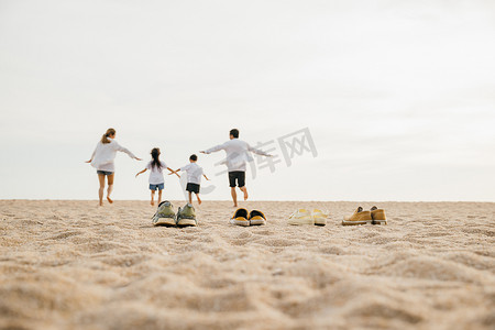 生活方式父亲、母亲和孩子脱鞋在沙子上奔跑