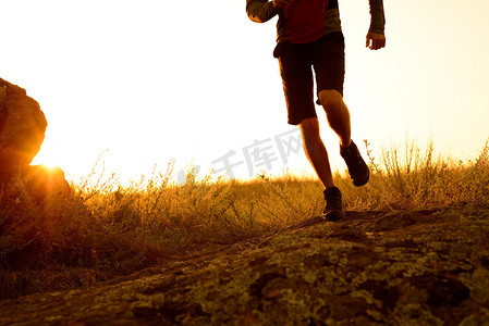 日落时在落基山小径上奔跑的运动员腿部特写。