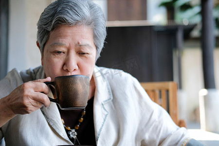 年长的老年妇女喝咖啡茶。