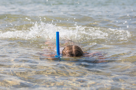 女孩带着面罩和通气管漂浮在水面上