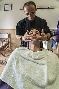 在西班牙安达卢西亚哈恩省萨比奥特的一家理发店剃须后，Barbero 在客户面前涂抹奶油