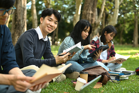亚洲学生读书，准备在大学校园的绿色草坪上考试。