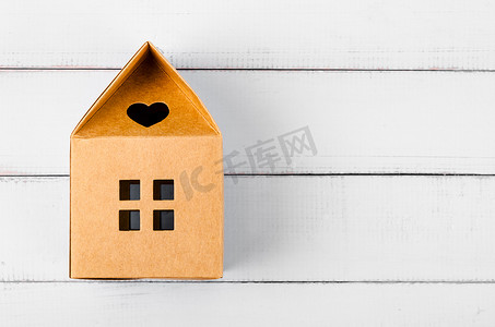 木制背景上的棕色纸房子折纸，空白空间可供您的文字或消息使用。