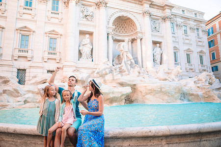 古代钱币摄影照片_旅行家庭在意大利罗马的特雷维喷泉投掷硬币以求好运。
