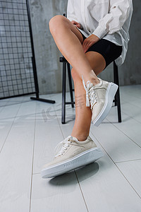 米色系摄影照片_穿着米色系带休闲运动鞋的女性修长双腿。