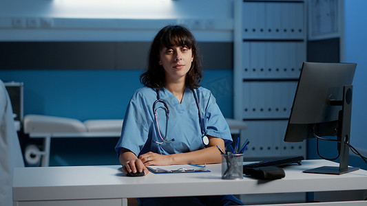 全科医生摄影照片_坐在办公桌前的全科医生护士在病人诊断报告上工作数小时