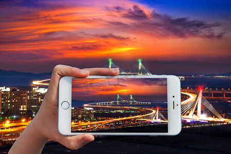 白色大桥摄影照片_手持智能手机在仁川大桥与太阳合影