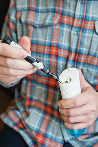 一名身穿格子衬衫的男子正在修理用于清洁牙齿的冲洗器。