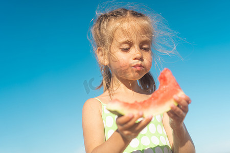 有趣的小女孩在海洋海滩吃西瓜阳光明媚的夏日。