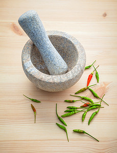 新鲜辣椒摄影照片_白色木制背景上的新鲜辣椒，配有研钵和研杵