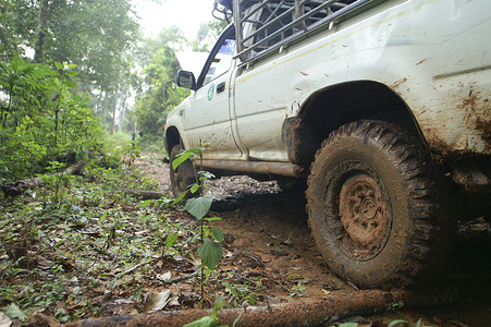 机器驾驶摄影照片_4x4 汽车在泥泞中上坡行驶的特写