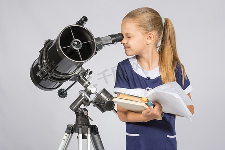 女学生透过望远镜看课本