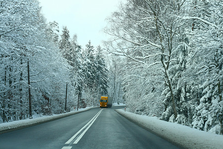 曲线黄色曲线摄影照片_通过多雪的森林的黄色卡车