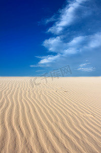 强风吹拂摄影照片_与蓝天的被风吹拂的沙丘