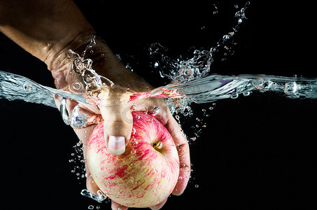 苹果静物摄影照片_手拿起溅在水中的苹果。