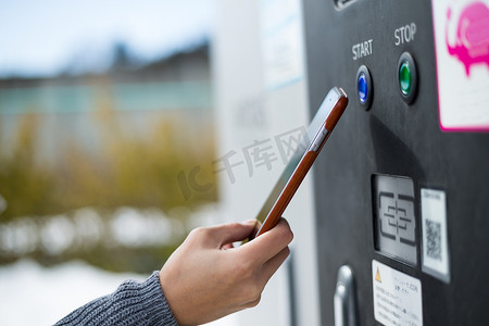 女性在户外通过 NFC 为汽车充电系统付费