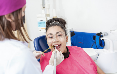 spe摄影照片_口腔科医生用钻头清洁病人女孩的嘴。