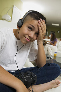 沮丧的男孩戴着耳机玩电子游戏