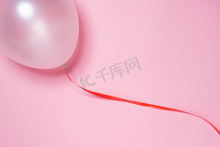 粉红色背景中突显的节日丝带和白色气球