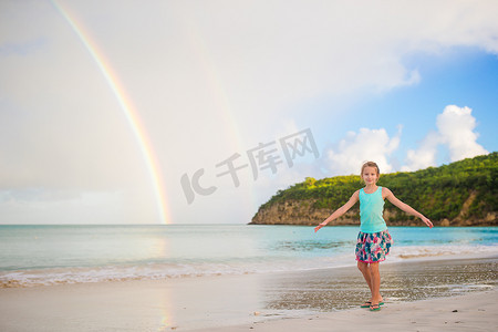 快乐的小女孩背景美丽的彩虹在海面上。