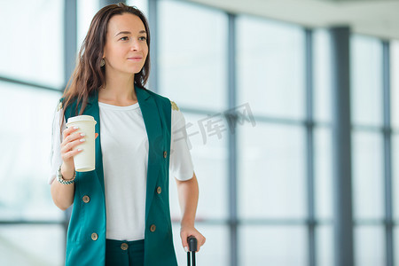 国际机场的年轻女子带着行李和咖啡走路去