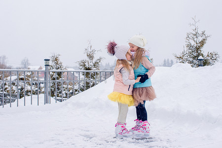 可爱的女孩在冬季雪天在户外溜冰场滑冰