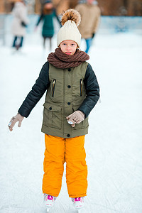 可爱的小女孩在冬天的雪天去户外滑冰