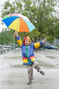 雨水花摄影照片_站在雨中打伞的男孩