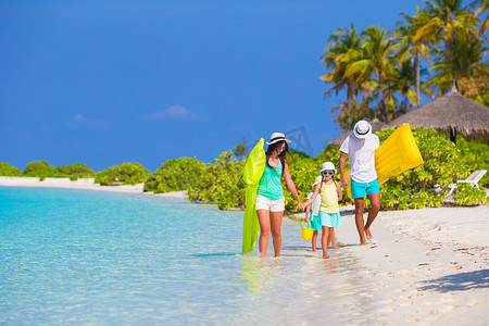 白色沙滩上带气垫的幸福美丽家庭
