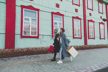 年轻的购物狂朋友女性朋友带着快乐和微笑在街头春天或冬天的城市散步和提着购物袋 — 购买和空闲时间概念
