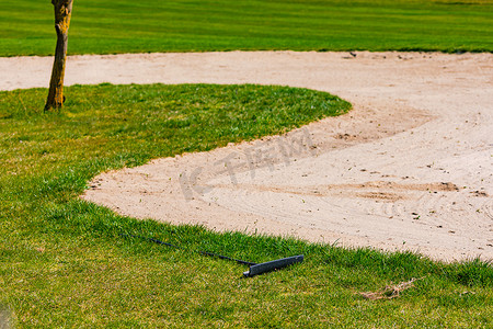 沙坑摄影照片_一个德国高尔夫球场，草坪维护良好，沙坑内有耙子，可以去除造成的痕迹