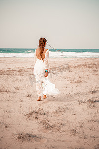 在沙滩上穿着白色长裙和银首饰的波西米亚风格模特。