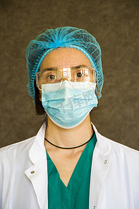 护士戴口罩摄影照片_女医生肖像，戴面具、眼镜、手套和制服的医生。