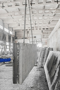 在一家工业企业的钢筋生产中，一名建筑工人的手用链条支撑着提升机上的一块大混凝土板